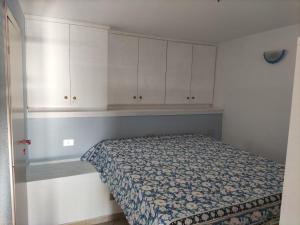 um pequeno quarto com uma cama e armários brancos em TancaManna16 em Cannigione