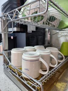 a dish rack full of mugs in a kitchen at Thetamu Homestay مسلم Pesona in Jalan Baharu