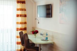 een tafel met twee stoelen en een televisie aan de muur bij Hotel Sonnental in Neusorg