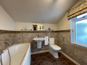 uma casa de banho com um lavatório, um WC e uma banheira em Spa Cottage em Braithwaite