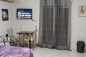 Schlafzimmer mit einem Bett, einem Tisch und einem TV in der Unterkunft Fotini studio in Thessaloniki