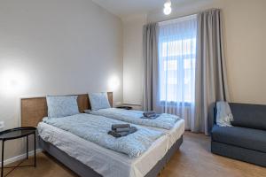 a bedroom with a bed and a couch and a window at Dandelion Apartments Ģertrūdes in Rīga