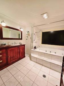uma grande casa de banho com banheira e uma grande televisão em The Gamekeepers Cottage em Mount Tamborine