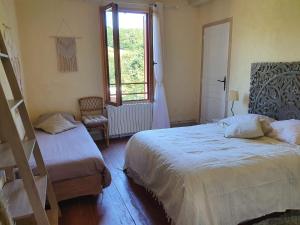 a bedroom with two beds and a window at La Maison du Bonheur in Anlhiac