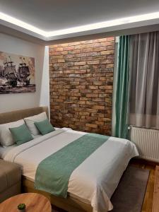 1 dormitorio con cama y pared de ladrillo en Lux Apartman Kovačević, en Jagodina
