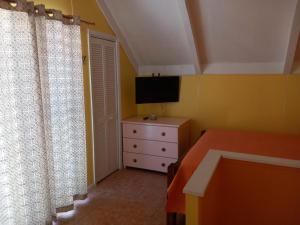 a bedroom with a bed and a dresser with a television at Sealofts On The Beach in Frigate Bay