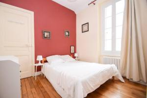 a bedroom with a white bed and a red wall at Appt 5 pers au coeur de Dinard classé 2 étoiles in Dinard