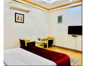 - une chambre avec un lit, une télévision et une table dans l'établissement Awadh Inn ,Lucknow, à Lucknow