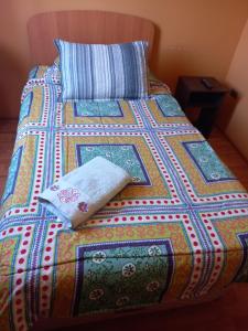 ein Bett mit einer bunten Decke und einem Kissen darauf in der Unterkunft HOSTAL LA CASONA ALFREDO CAMPOS in Ovalle