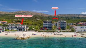a beach with people in the water and buildings at VIPo Prestige Apartments in Podstrana