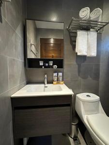 a bathroom with a sink and a toilet and a mirror at Coron 180 Hotel in Coron