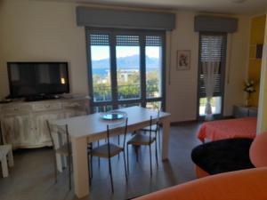 sala de estar con mesa, sillas y TV en Villa La Magnolia - Private Beach Access, Garden, Views, en Lazise