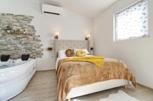 a white bedroom with a bed and a bath tub at Aux 3 Glands - Nature & Spa in Dieffenbach-au-Val