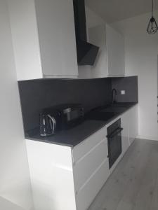 a kitchen with white cabinets and a black counter top at APARTAMENT OLIWIER in Kłodzko