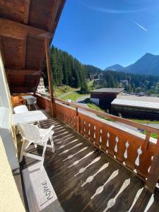 a wooden deck with a chair and a table on it at Furkablick Alice und Yvonne by Arosa Holiday in Arosa