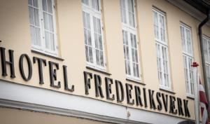 una señal en el lateral de un edificio con ventanas en Frederiksværk Hotel en Frederiksværk