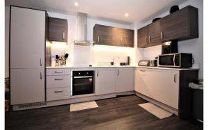 a kitchen with white appliances and wooden cabinets at Rent Luxuri - Luxury 2 bed Apartment in Leicester