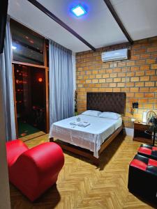 a bedroom with a bed and a red chair at MORALES BUNGALOWS in Tarapoto