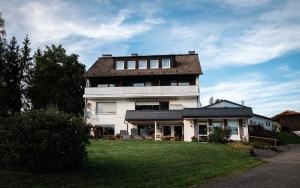 ein großes weißes Haus mit einem Dach auf einem Rasen in der Unterkunft Bauernhofpension Hof Dödesberg in Bad Berleburg