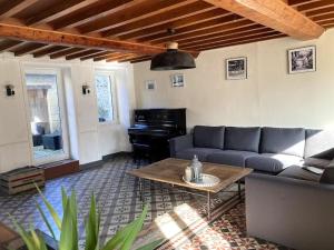 sala de estar con sofá y piano en Maison de campagne proche Omaha Beach, en Formigny