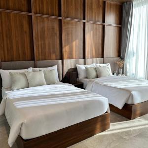 two beds in a room with wooden walls at TANA Beach Villas in Lian