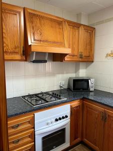 cocina con armarios de madera y horno de fogón blanco en Casa playa Piles, en Piles