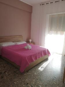 um quarto com uma cama com um cobertor rosa em Malatesta House em Roma
