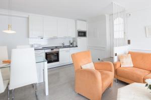 a living room with white cabinets and orange chairs at Windeby 7E in Wenningstedt
