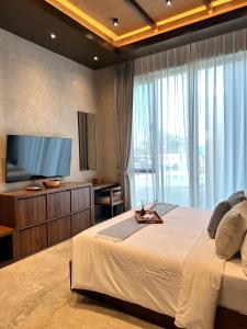 a bedroom with a large bed and a flat screen tv at TANA Beach Villas in Lian