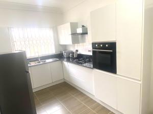 a kitchen with white cabinets and a black appliance at Sanctuary House in Accra
