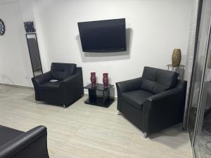 a living room with two chairs and a flat screen tv at Hermoso apartmento con La mejor vista el peñol guatape in Guatapé