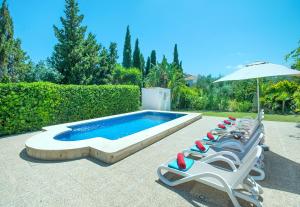 a row of lounge chairs and a pool with an umbrella at Owl Booking Villa Bocoris - 15 Min Walk to the Beach in Port de Pollensa