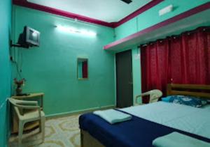 ein Schlafzimmer mit einem Bett, einem Stuhl und einem TV in der Unterkunft Serina House Malvan in Malvan