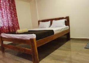 ein Bett in einem Schlafzimmer mit einem roten Vorhang in der Unterkunft Serina House Malvan in Malvan