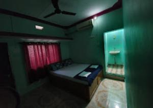 kleines, grünes Zimmer mit einem Bett und einem Fenster in der Unterkunft Serina House Malvan in Malvan