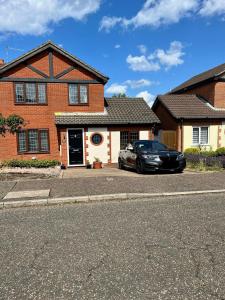 a black car parked in front of a brick house at SeaCross Sheringham Norfolk Coast 3 Bed Detached house in Sheringham