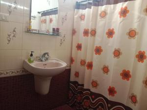 a bathroom with a sink and a shower curtain with flowers at Pournami Home Stay in Trichūr
