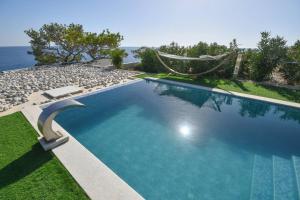 a swimming pool with a hammock next to the ocean at ocean Island villa Achlia in Ierapetra