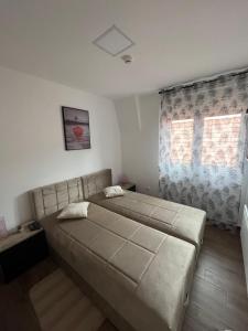 - une chambre avec un grand lit et une fenêtre dans l'établissement Ajrin Apartman Kopaonik, à Kopaonik