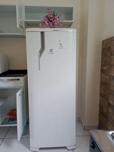 a white refrigerator with flowers on top of it at Apartamento Aconchego da Serra Azul in Barra do Garças