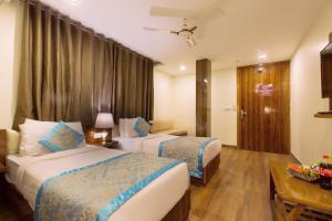 una camera d'albergo con due letti e un tavolo di OPO Hotel Viva Palace a Nuova Delhi