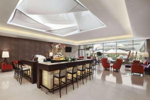 a lobby with a bar with red chairs at Ramada by Wyndham Bucharest Parc Hotel in Bucharest