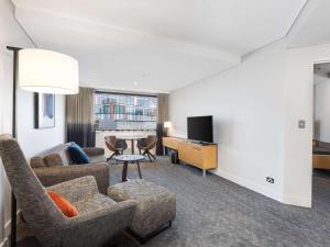 a living room with a couch and chairs and a table at Novotel Sydney Darling Harbour in Sydney