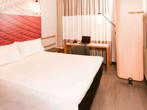 a bedroom with a bed and a desk with a laptop at ibis Campo Grande in Campo Grande