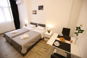 2 Betten in einem Zimmer mit einem Tisch und einem Schreibtisch in der Unterkunft Sites Of Zadar Rooms in Zadar