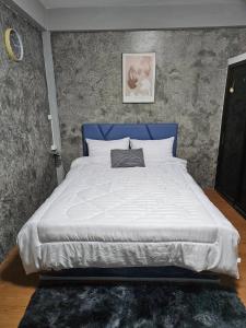 a large bed with a blue headboard in a bedroom at Hommie by De-A-Ga in Ban Bang Talat