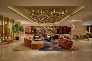 eine Lobby mit Sofas, Stühlen und einem Kronleuchter in der Unterkunft London Hilton on Park Lane in London