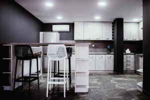 a kitchen with white cabinets and bar stools at Guesthouse The Rock in Sapareva Banya