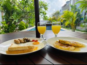 two plates of breakfast food and two glasses of orange juice at Maliqa Villas Nusa Penida in Nusa Penida