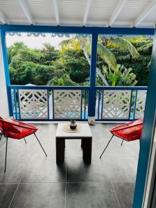 d'un balcon avec une table et deux chaises rouges. dans l'établissement *Secret Sand* Cheerfull Town beach house villa, à La Baie-Orientale